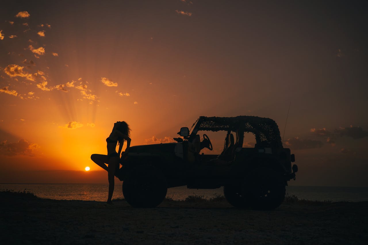 silhouette de femme au coucher de soleil s'appuyant contre une voiture